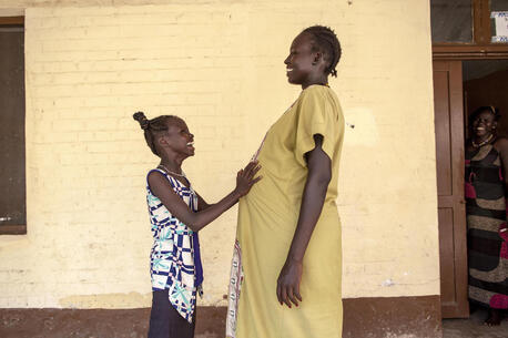 Eleven-year old Nyanyiik rests her hands on the stomach of Sundoay John - who is 9 months pregnant with her second child - outside the UNICEF-supported maternity ward at Malakal Teaching Hospital, South Sudan.