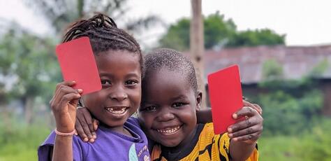 In Kwango Province, Democratic Republic of the Congo (DRC), 5-year-olds Makiese, left, and Madinu brandish red cards after receiving their polio vaccinations in 2023.